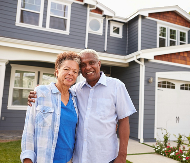 elderly couple in front of home